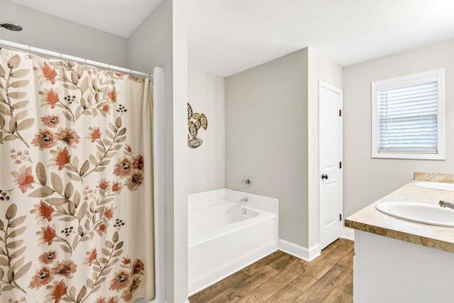bathroom featuring wood finished floors, a bath, double vanity, baseboards, and curtained shower