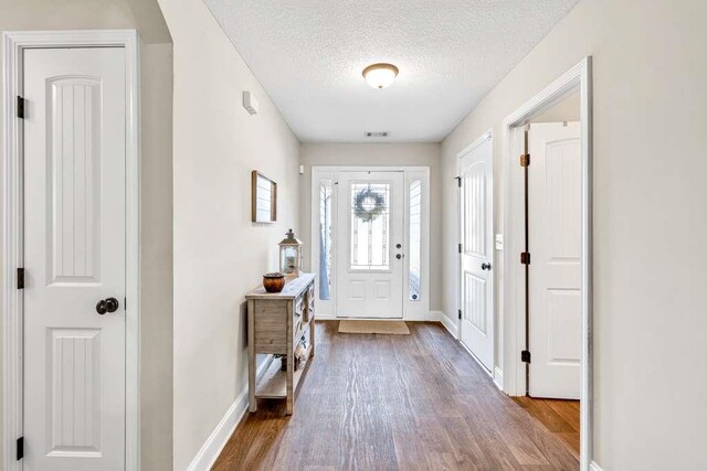 entryway with dark wood finished floors, a textured ceiling, and baseboards