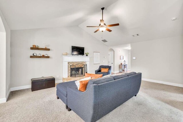 living area featuring a fireplace with raised hearth, a ceiling fan, vaulted ceiling, arched walkways, and carpet