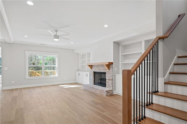 unfurnished living room with light wood-style flooring, a fireplace, baseboards, and ceiling fan