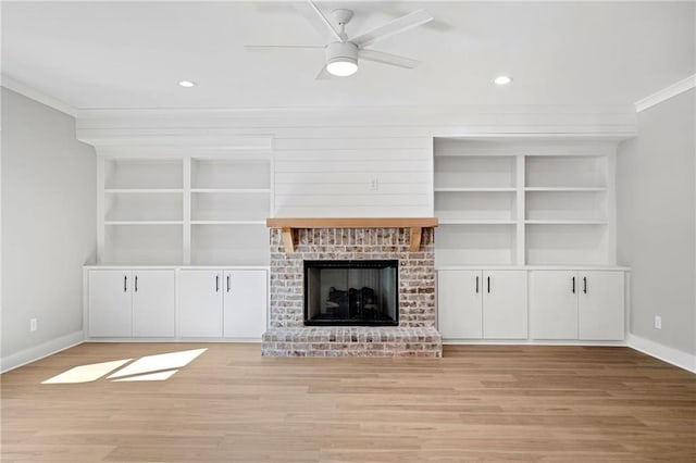 unfurnished living room featuring baseboards, built in features, a brick fireplace, light wood finished floors, and crown molding