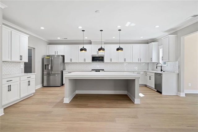 kitchen with appliances with stainless steel finishes, a center island, light countertops, and a sink