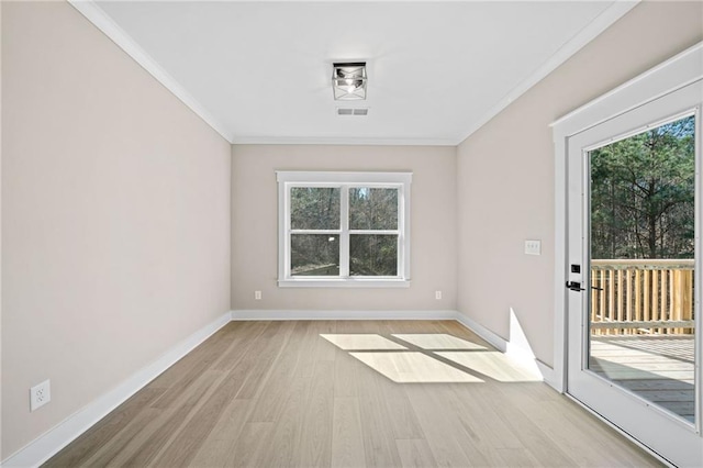 empty room with ornamental molding, wood finished floors, visible vents, and baseboards