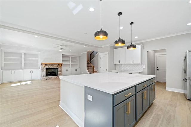 kitchen with a ceiling fan, ornamental molding, freestanding refrigerator, light wood-type flooring, and white cabinetry