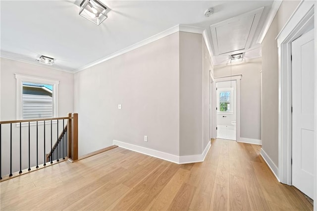 interior space featuring light wood-style floors, attic access, crown molding, and an upstairs landing