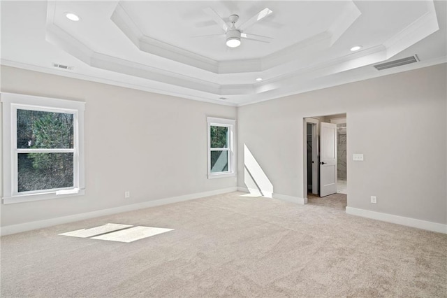 spare room with light carpet, a raised ceiling, visible vents, and crown molding