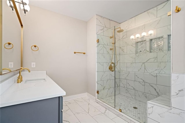 full bath featuring marble finish floor, double vanity, a sink, tiled shower, and baseboards