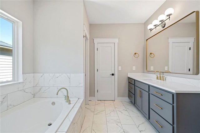 bathroom with marble finish floor, a garden tub, vanity, and baseboards