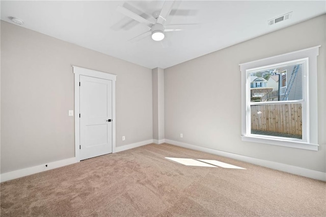 carpeted spare room with ceiling fan, visible vents, and baseboards