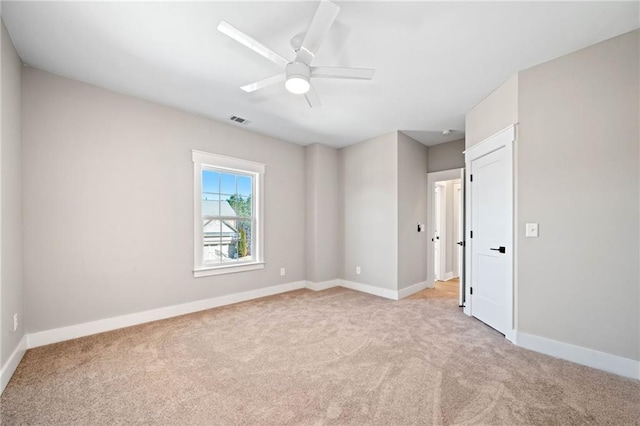 empty room featuring light carpet, baseboards, visible vents, and a ceiling fan