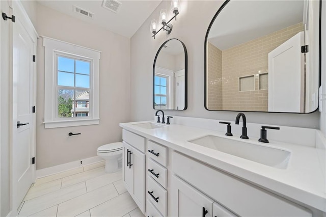 bathroom with toilet, a sink, and visible vents