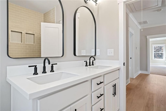 bathroom featuring double vanity, wood finished floors, a sink, and crown molding