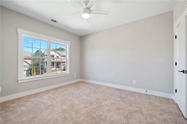 carpeted spare room featuring ceiling fan, visible vents, and baseboards