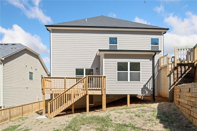 back of house featuring a deck, a fenced backyard, a shingled roof, and stairway