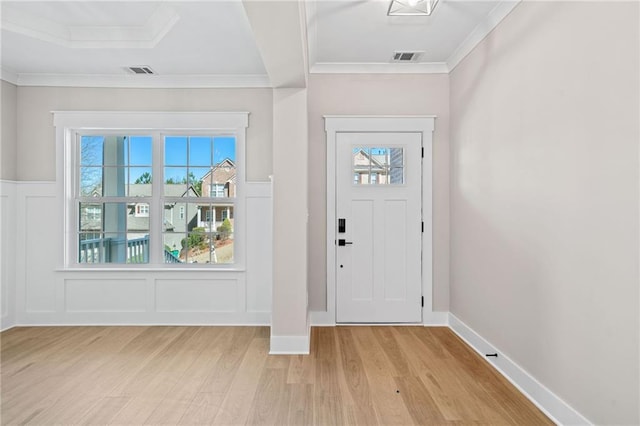 foyer entrance featuring light wood-style flooring, visible vents, a decorative wall, and ornamental molding