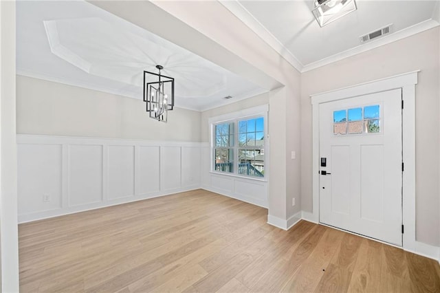 entrance foyer with light wood-type flooring, visible vents, crown molding, and a decorative wall