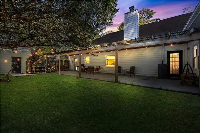 back house at dusk with a yard and a patio area