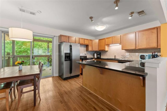 449 Clairemont Ave Unit H3, Decatur, GA 30030 - kitchen with appliances with stainless steel finishes, a peninsula, tasteful backsplash, light wood finished floors, and dark countertops
