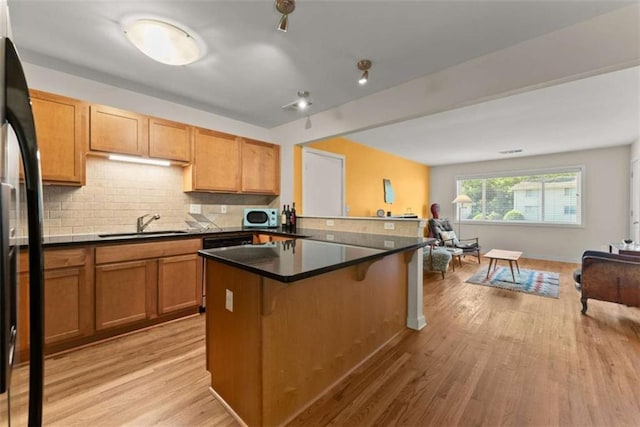 449 Clairemont Ave Unit H3, Decatur, GA 30030 - kitchen featuring light wood finished floors, a breakfast bar area, freestanding refrigerator, backsplash, and dark countertops