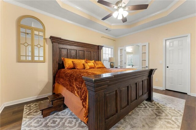 bedroom with wood-type flooring, a tray ceiling, ceiling fan, and crown molding