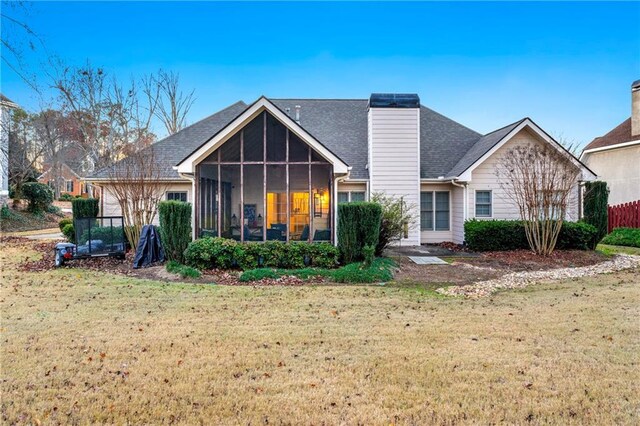 rear view of house featuring a yard and a sunroom