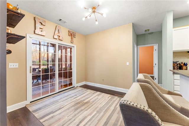 living area featuring a chandelier, light hardwood / wood-style floors, and a textured ceiling