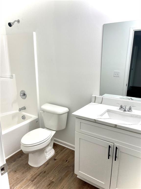 full bathroom with hardwood / wood-style floors, vanity, bathtub / shower combination, and toilet