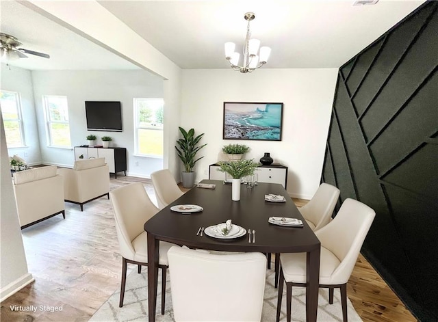 dining room with ceiling fan with notable chandelier, light hardwood / wood-style flooring, and a healthy amount of sunlight