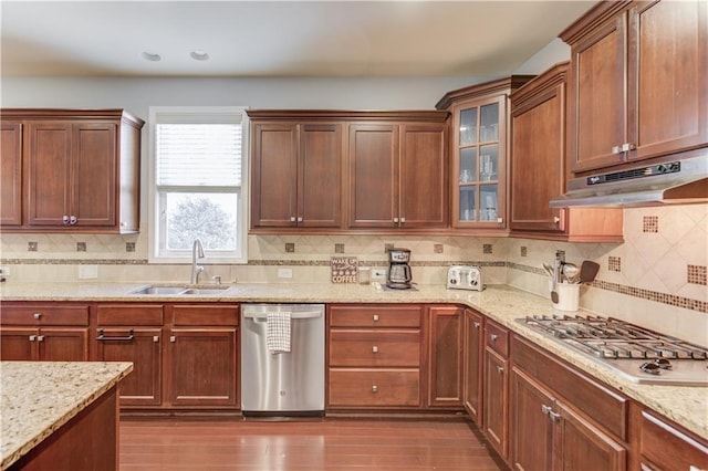 kitchen with appliances with stainless steel finishes, dark hardwood / wood-style floors, tasteful backsplash, sink, and light stone countertops