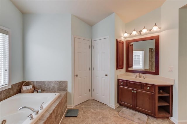 bathroom with vanity, a relaxing tiled tub, and tile patterned floors