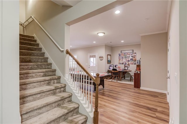 stairway with crown molding and wood-type flooring