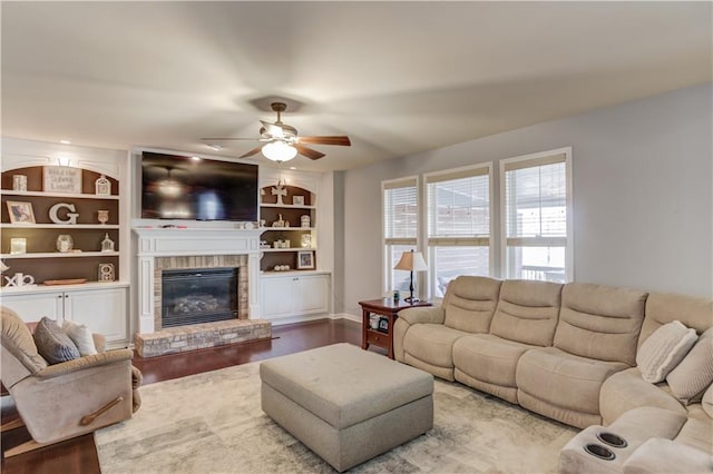 living room featuring hardwood / wood-style floors, built in shelves, a brick fireplace, and ceiling fan