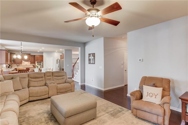 living room featuring ceiling fan with notable chandelier and wood-type flooring