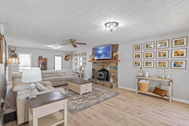 living room featuring ceiling fan, light hardwood / wood-style floors, and a textured ceiling