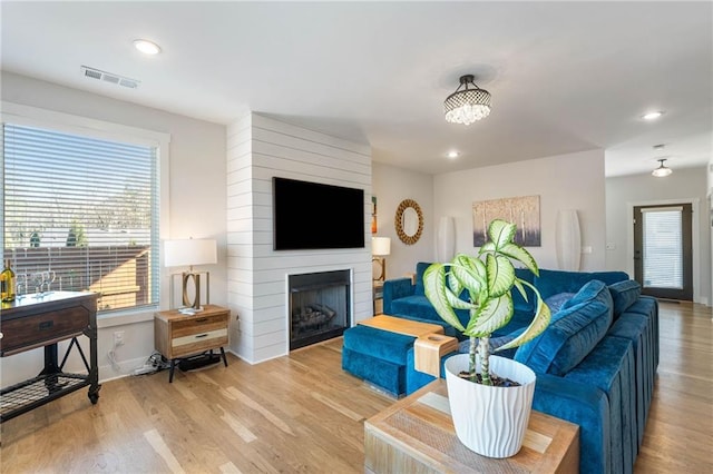 living room with plenty of natural light, a large fireplace, and light wood-type flooring