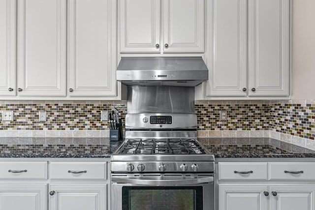 kitchen featuring backsplash, white cabinets, dark stone countertops, stainless steel gas range oven, and exhaust hood