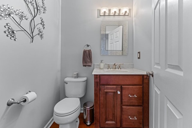 bathroom with toilet, baseboards, and vanity