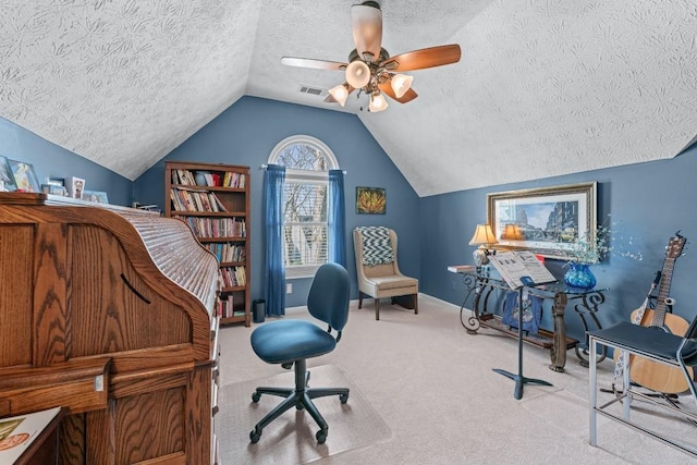 office featuring lofted ceiling, a textured ceiling, carpet floors, visible vents, and a ceiling fan