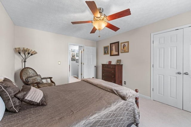 bedroom with a closet, light colored carpet, ceiling fan, a textured ceiling, and baseboards