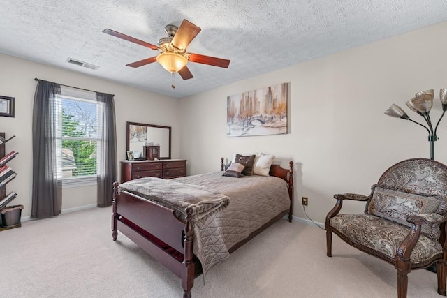 bedroom featuring a textured ceiling, light colored carpet, a ceiling fan, baseboards, and visible vents