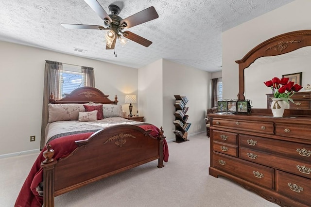 bedroom featuring light carpet, baseboards, visible vents, and a textured ceiling