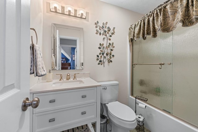 bathroom with combined bath / shower with glass door, vanity, and toilet