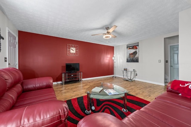 living area featuring a textured ceiling, wood finished floors, and baseboards