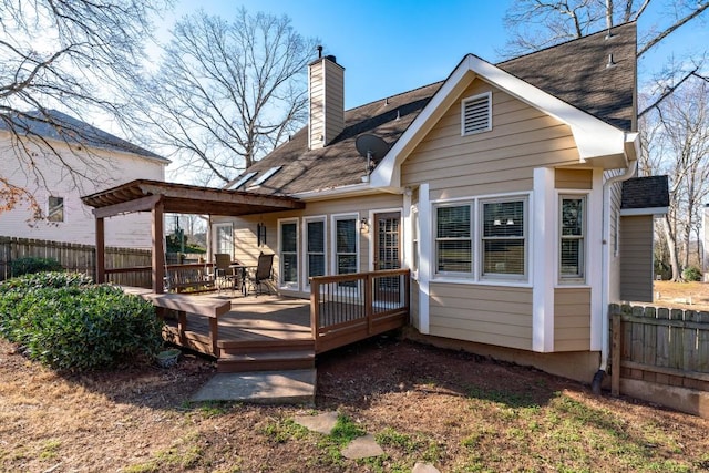 rear view of property featuring fence, a chimney, and a wooden deck