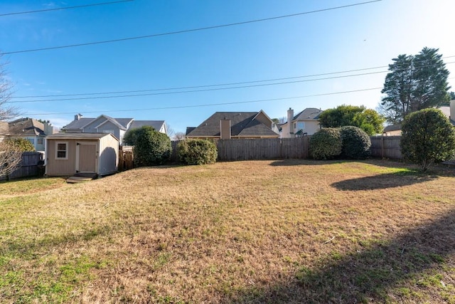 view of yard featuring a fenced backyard, a shed, and an outbuilding