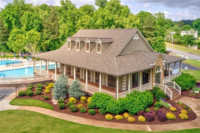 view of front of house featuring a porch, roof with shingles, and a community pool