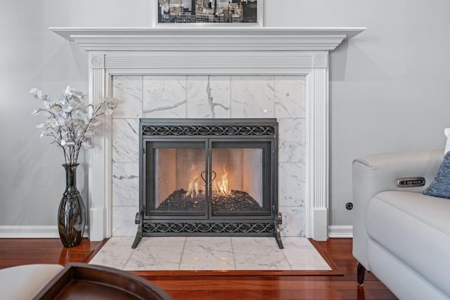 details with a tile fireplace and wood finished floors