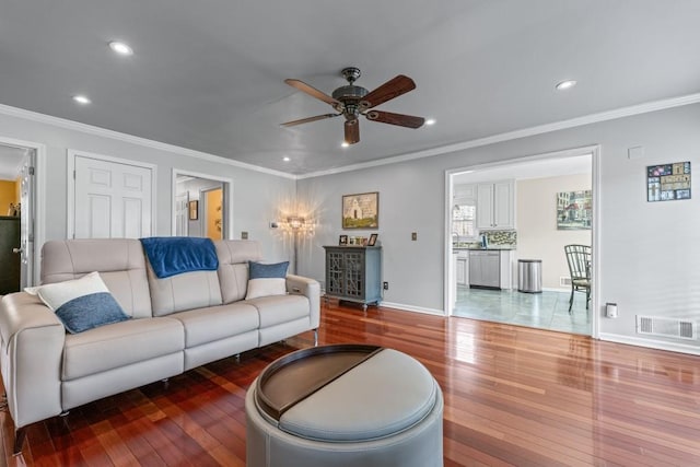 living room featuring recessed lighting, wood-type flooring, visible vents, and crown molding