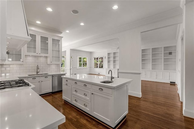 kitchen with stainless steel appliances, white cabinetry, sink, and a kitchen island with sink