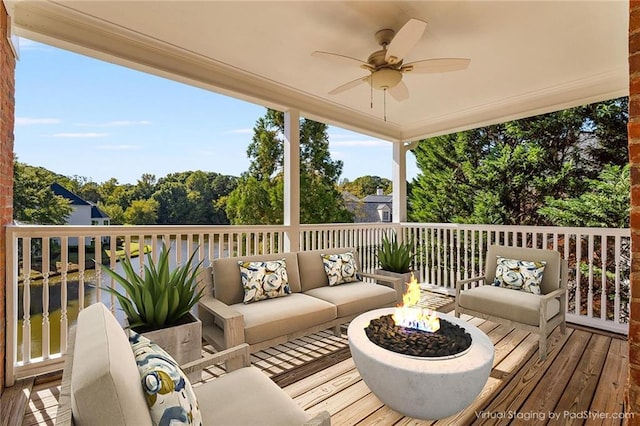 wooden terrace featuring ceiling fan and an outdoor living space with a fire pit